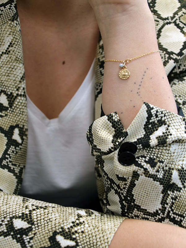 Esquema Pulsera de oro con signo astrológico y encanto de piedras preciosas.