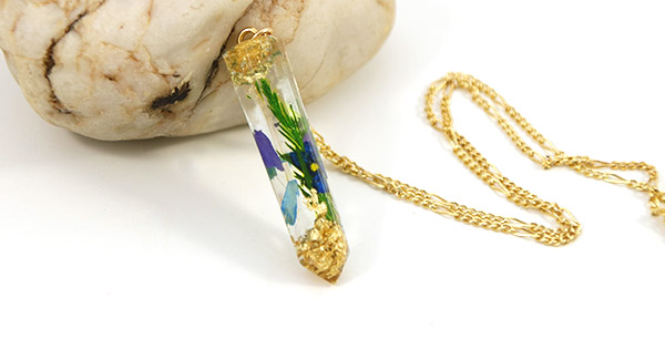 Colgante de resina con pan de oro y plantas.