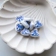 Cuenta de cerámica corazón 15x14,5 mm - motivo lazo - Blanco - Azul x1